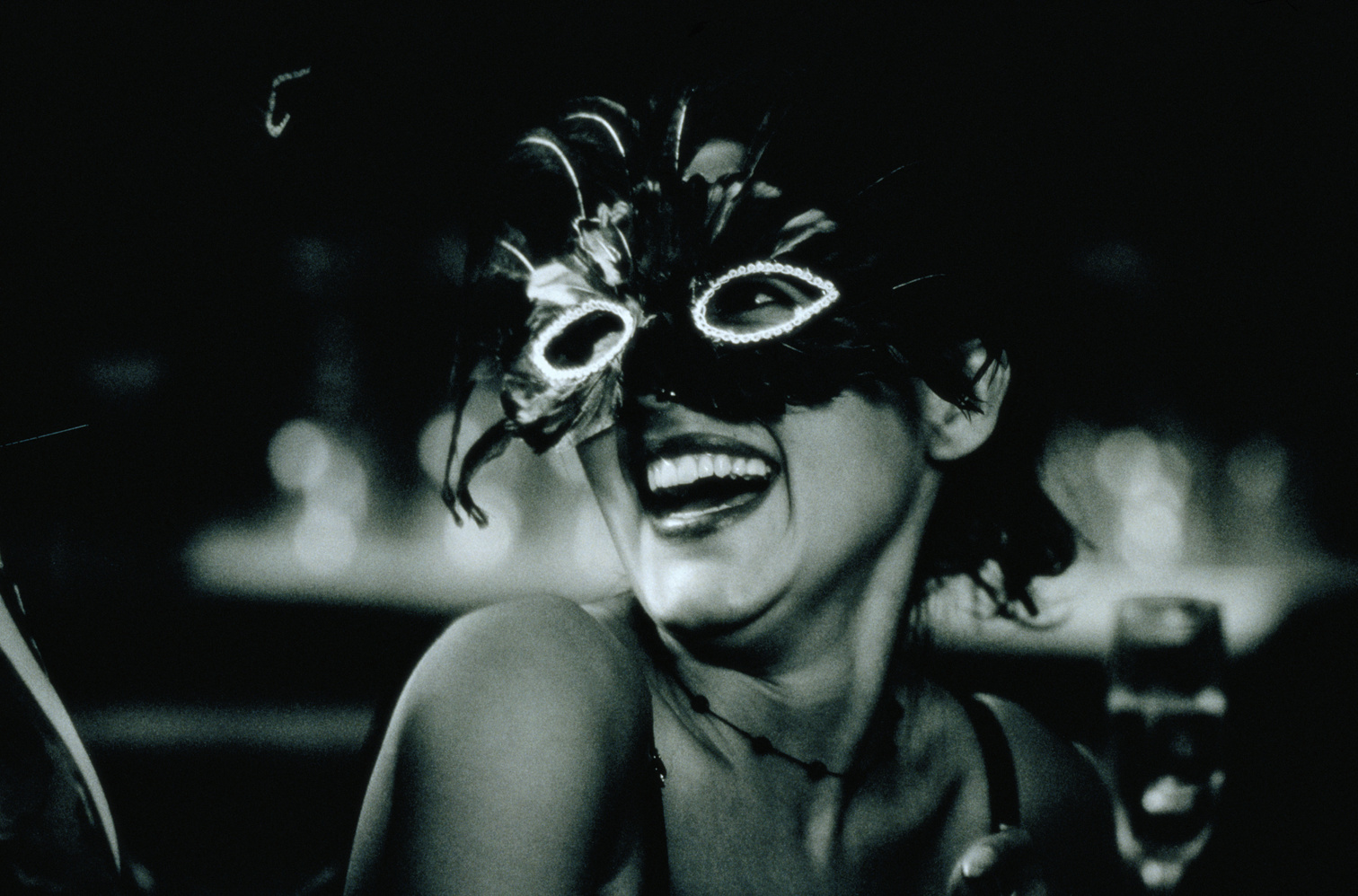 Young woman in masquerade laughing, close-up (B&W)